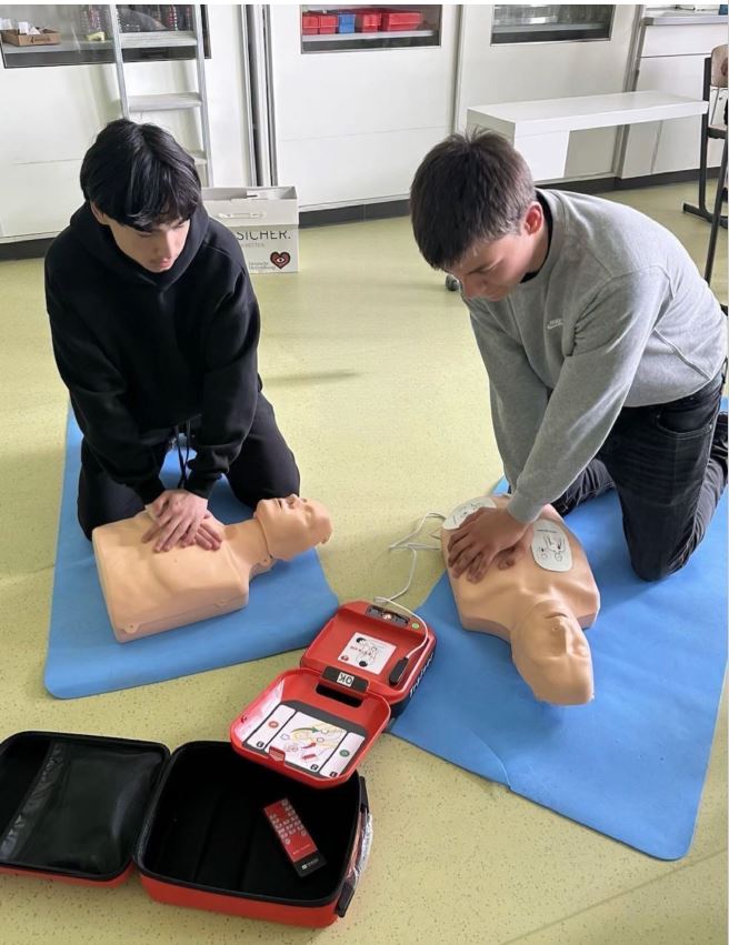 Das Bild zeigt zwei Personen, die an Reanimationspuppen eine Herzdruckmassage üben.